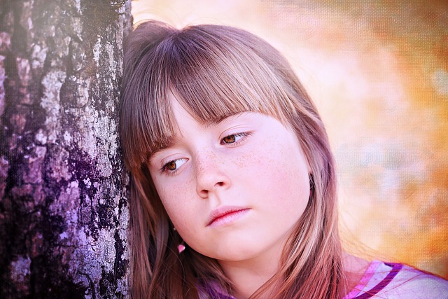 young girl leaning on a tree looking contemplative