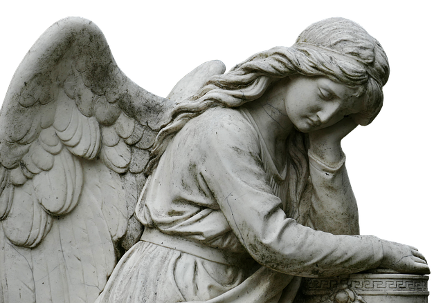 A sad looking stone angel carved as part of a gravestone in a cemetery.