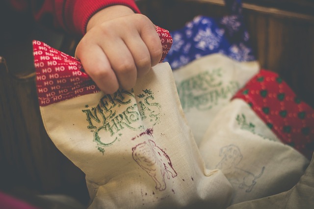 A close-up of a child's hand, holding one of several Christmas treat bags.