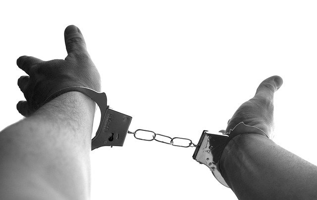 A picture of a person's hands in handcuffs, reaching out as if looking to be freed.