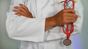Close up of a doctor in a lab coat, standing with his arms crossed.